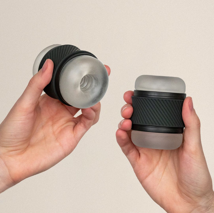 Two hands holding the Bswish bhandy classic clear silicone and black masturbation penis stroker toy