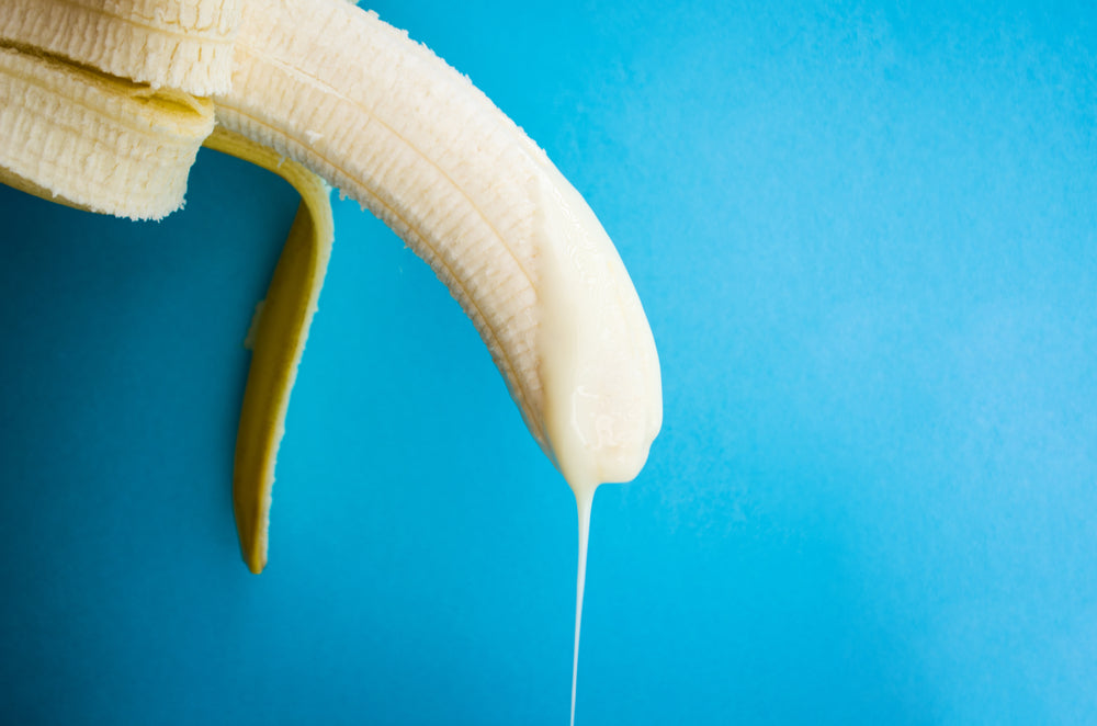 A banana drips something white, meant to evoke semen. Blue background. 