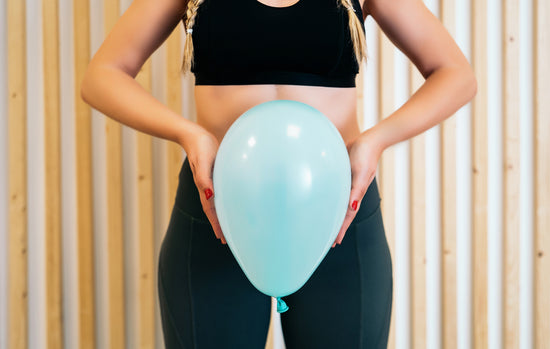A woman holds a balloon over her pelvic region 