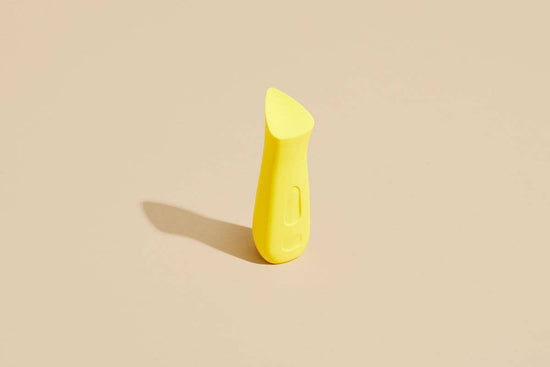 Kip lemon lipstick vibe, a cute yellow vibe that fits in your hand stands upright on a tan background