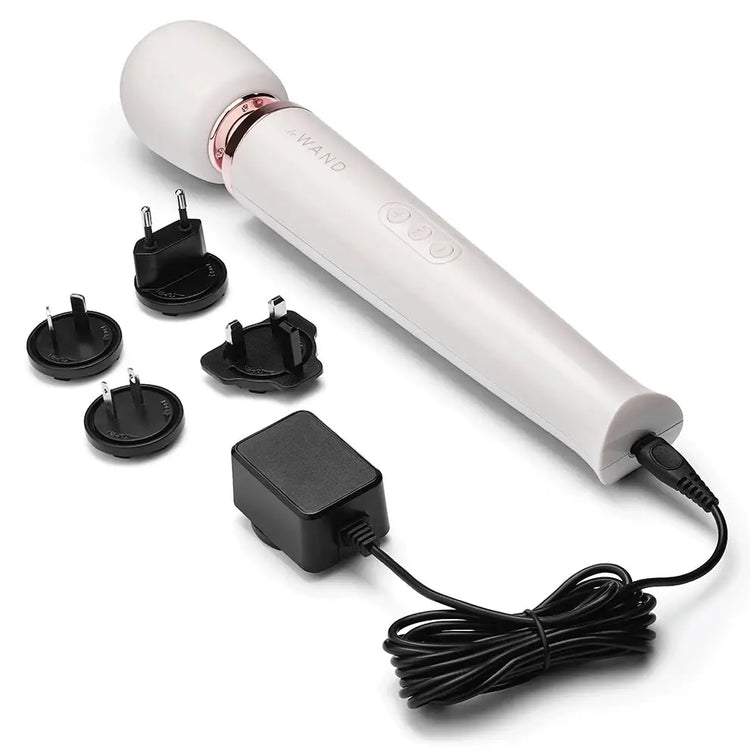 A white Le Wand Rechargeable massager, vibrator is pictured on a white background The charging cord and alternative plugs are also shown